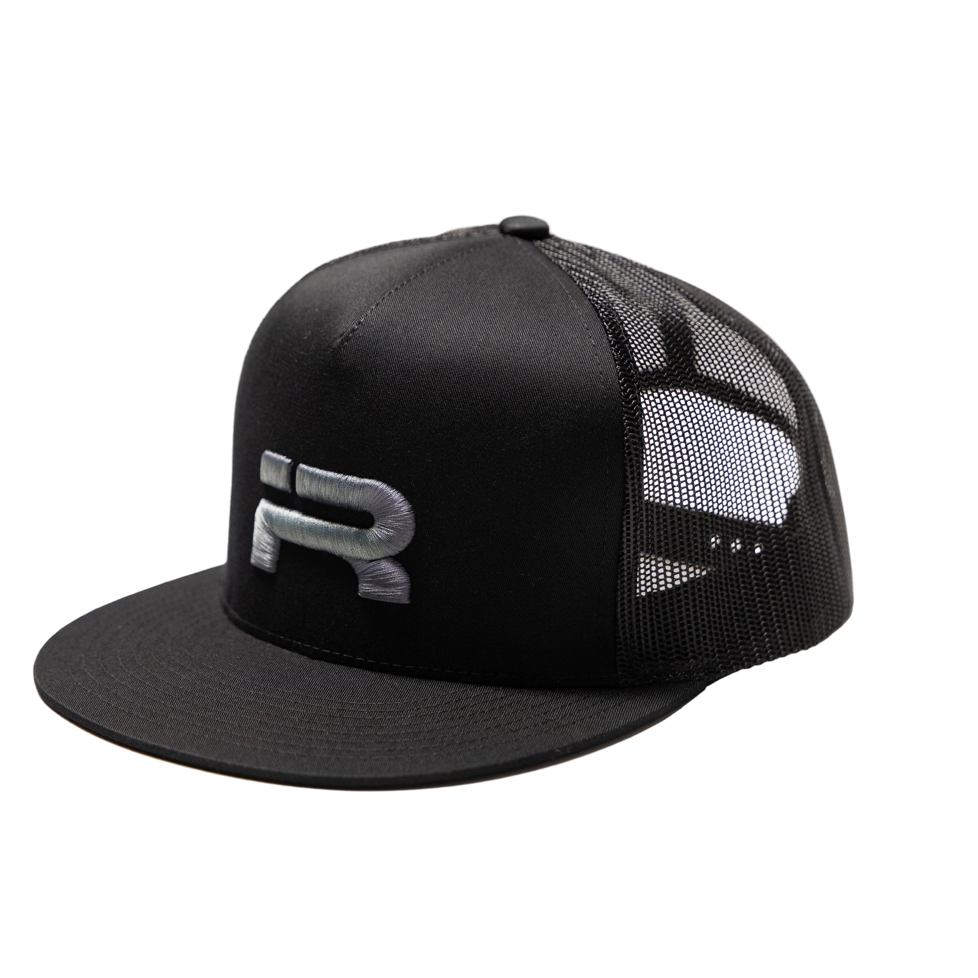 A black trucker-style snapback cap with a structured black front panel, black flat brim, and black mesh back panels. A stylized silver 'R' logo is embroidered on the front panel.